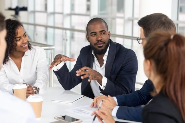 A photo of a group of diverse faculty sitting at a table