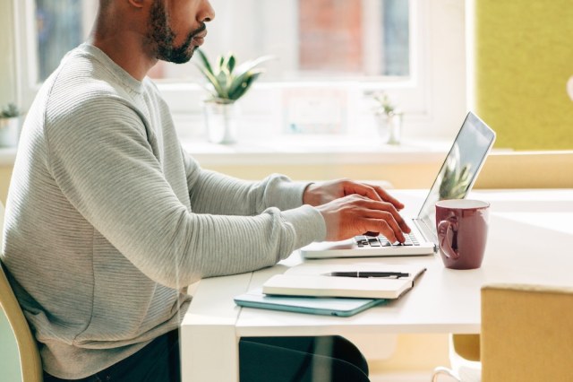 A man sitting at a desk using a laptop